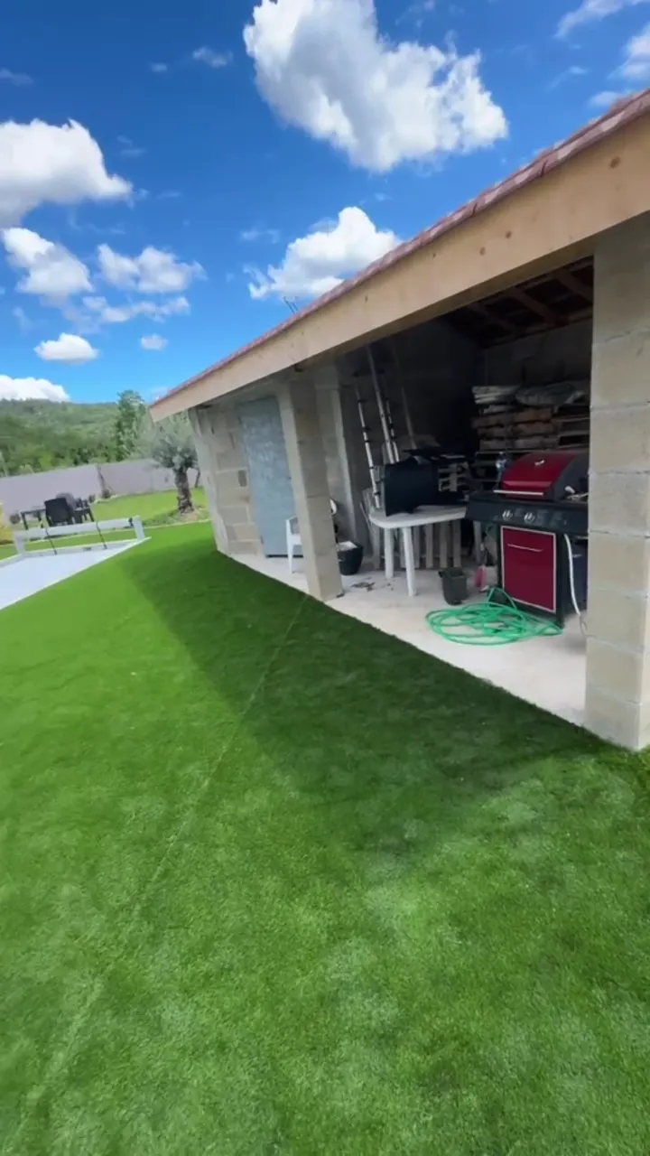 Piscine terminée avec plage en travertin, pool house et gazon synthétique